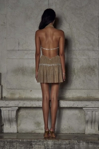 Dettaglio dell'abito mini con paillettes color oro champagne, schiena nuda e strass lucidi