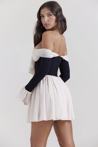 Detail of a backless black and white mini dress with pleated hem and off-shoulder sleeves