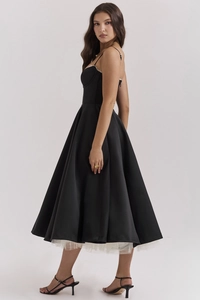 Dettaglio di un abito midi in raso nero con orlo in tulle bianco e taglio aderente in vita