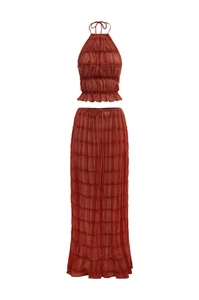 Detail of rust-colored halter crop top and ruched maxi skirt with ruffled texture