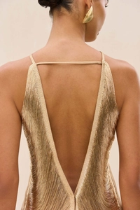 Détail de la robe dorée à franges montrant le dos nu et la texture fluide métallisée