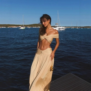 Elegant champagne two-piece beach set featuring off-shoulder draped top and pleated maxi skirt