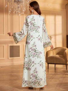 Detail of embroidered cuffs with gold sequins on a white floral print maxi dress