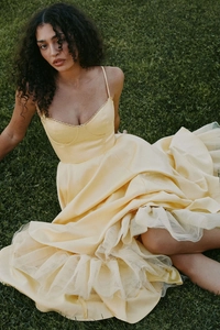 Détail d'une robe de soirée jaune clair à fines bretelles et jupe en tulle multicouche