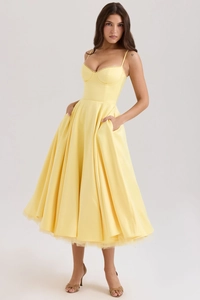 Détail de la robe en satin jaune clair avec bustier structuré et jupe plissée