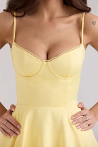 Gros plan d'une robe de soirée jaune pâle avec bustier et bordure en dentelle fine