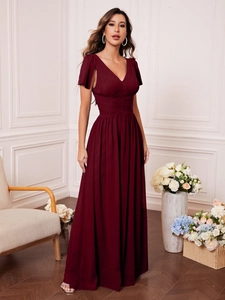 Detail of elegant burgundy V-neck evening gown featuring ruched bodice and flowing cap sleeves