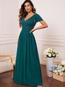 Detail view of deep green V-neck evening gown with chiffon ruffles and waist pleats