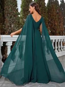 Detail of elegant dark green formal gown featuring a sheer cape and V-neck back design