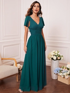 Detailed close-up of dark green V-neck evening gown with pleated waist and flutter sleeves