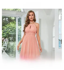 Gros plan sur une robe longue dos nu rose pêche avec détails ajourés et mousseline plissée