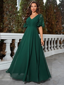 Détail d'une robe longue élégante en mousseline vert foncé avec col V et dentelle