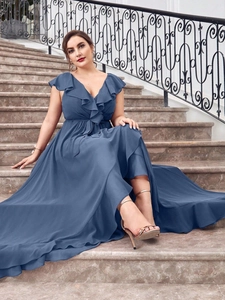 Elegant blue maxi dress with V-neckline and ruffled shoulders on stone stairs