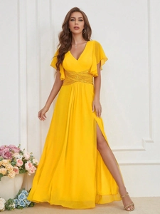 Détail de la robe en mousseline jaune avec ceinture à paillettes et fente haute au jambe