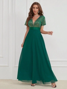 Détail de la robe en mousseline vert foncé avec corsage à paillettes dorées géométriques