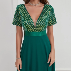 Detail of elegant V-neck evening dress with gold sequin pattern and green satin waistband