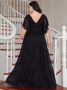 Rear view of plus size black V-neck maxi dress with flutter sleeves on spiral stairs