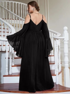 Detail view of elegant black cold-shoulder evening dress with flounce sleeves on a staircase