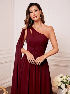 Détail d'une robe de soirée en mousseline bordeaux avec manche cape élégante et taille plissée