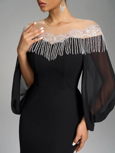 Detail of silver sequin embroidery and fringe tassels on a black luxury evening dress