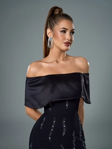 Detailed view of the off-shoulder black evening gown with sequin wavy patterns and satin ruffles
