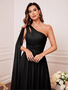 Détail de robe de soirée noire asymétrique avec manche drapée et plis à la taille