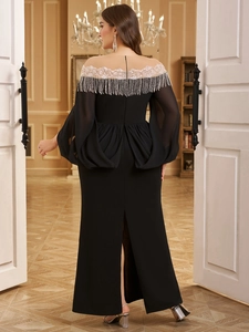 Detail of elegant black evening gown featuring intricate silver fringe and white embroidery