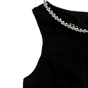 Close-up of elegant black dress neckline with white pearls and sparkling rhinestone trim