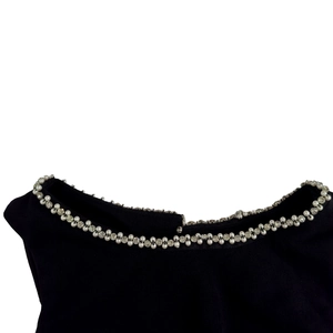 Detail of the black neckline featuring double rows of white pearls and sparkling rhinestones