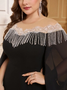 Close-up of white lace embroidery and shimmering sequin tassels on the black evening gown