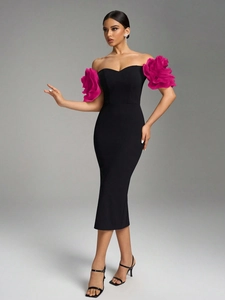 Detail of elegant off-shoulder black dress featuring dramatic rose pink floral ruffles