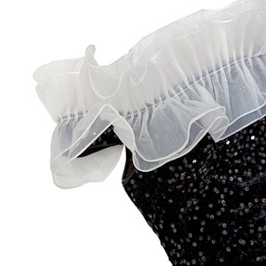 Détail de l'encolure avec volants en organza blanc et tissu en velours à paillettes noires