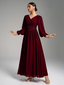 Détail de robe de soirée en mousseline bordeaux avec col en V, plis et taille ornée de paillettes