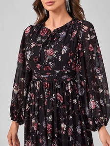 Détail d'une robe fleurie en mousseline avec manches lanternes et col à nœud délicat
