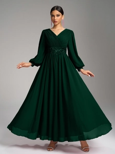 Détail du corsage plissé à col en V et de la taille perlée sur une robe vert foncé