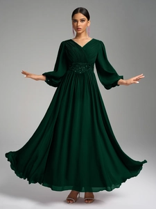 Détail du décolleté en V plissé et de la ceinture à paillettes sur cette robe de soirée verte