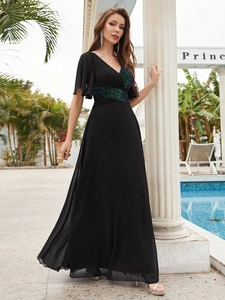 Détail du décolleté en V et des paillettes vertes sur la robe de soirée noire