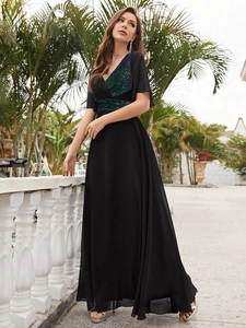 Détail du décolleté en V profond et des broderies de sequins verts sur la robe noire