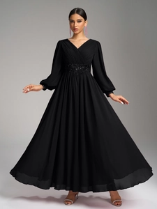 Détail du corsage plissé en V et de la ceinture à paillettes sur la robe en mousseline