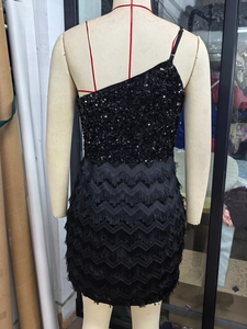 Détail de robe de soirée noire à une épaule avec sequins brillants et franges en forme de V