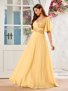 Détail d'une robe de soirée ambre avec col en V, sequins et manches à volants superposées