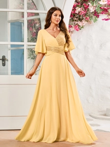 Détail du col en V d'une robe de soirée jaune avec paillettes dorées et volants