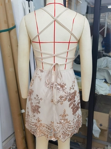 Detail view of champagne sequin dress featuring cross-strap backless design on mannequin