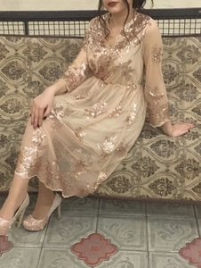 Détail de robe longue en mesh à paillettes champagne avec broderie florale et col en V