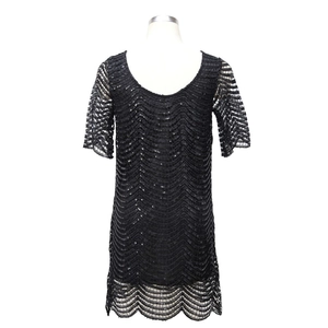 Dettaglio delle paillettes nere a onde su un abito da cocktail in tulle nero