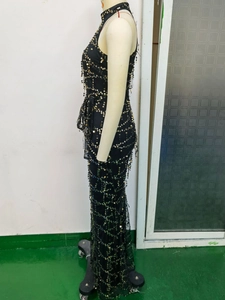 Détail d'une robe noire à paillettes montrant des sequins dorés et verts en motif filet