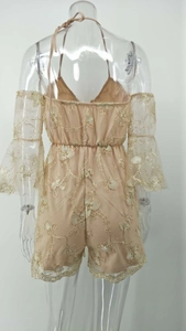 Détails de broderie florale dorée sur combinaison licou beige avec manches en dentelle