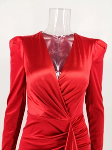 Detail of deep V-neck and ruched pleated satin fabric on a red long sleeve dress