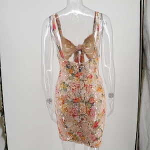 Detail of sequin floral mini dress featuring an open back and a large decorative bow