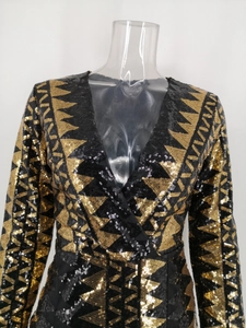 Detailaufnahme von V-Ausschnitt und geometrischen Goldpailletten auf dem langen Kleid